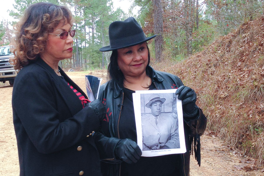 Catherine Walker Jones and Shirley Walker Wright hold a picture of their father, Clifton Walker, and stand on Poor House Road, where he was killed. (Photo by Admin)